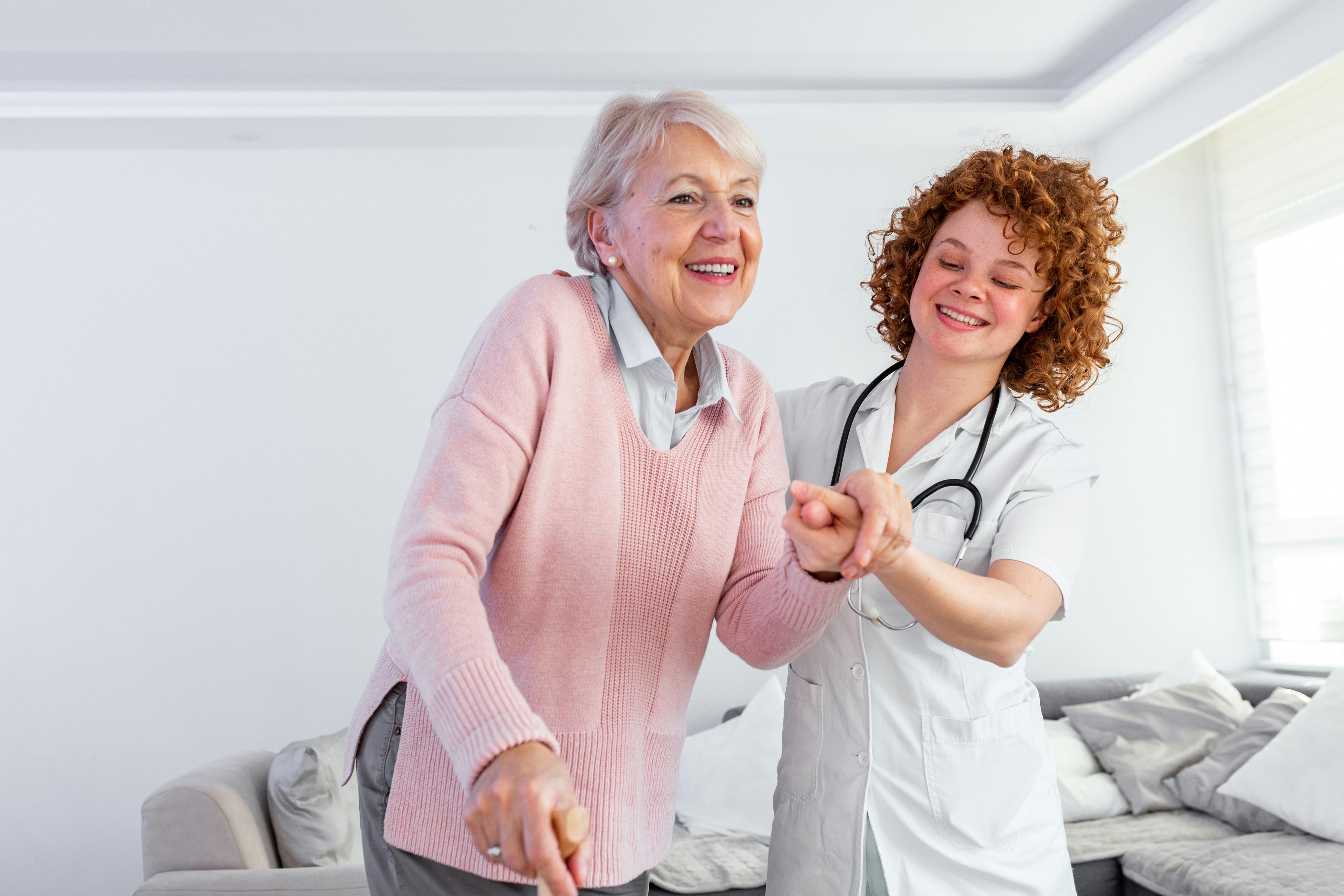 Senior woman with a cane being helped by a doctor, representing extended care insurance for ongoing recovery.